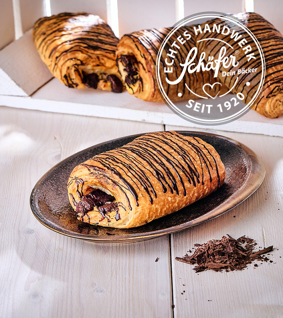 Gefülltes Schokoladencroissant mit Schokoladendekor auf Teller